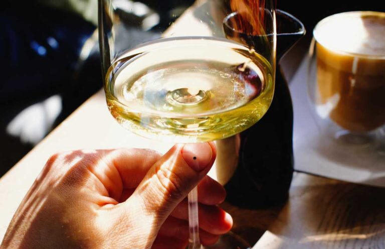 Hand holding glass of white wine