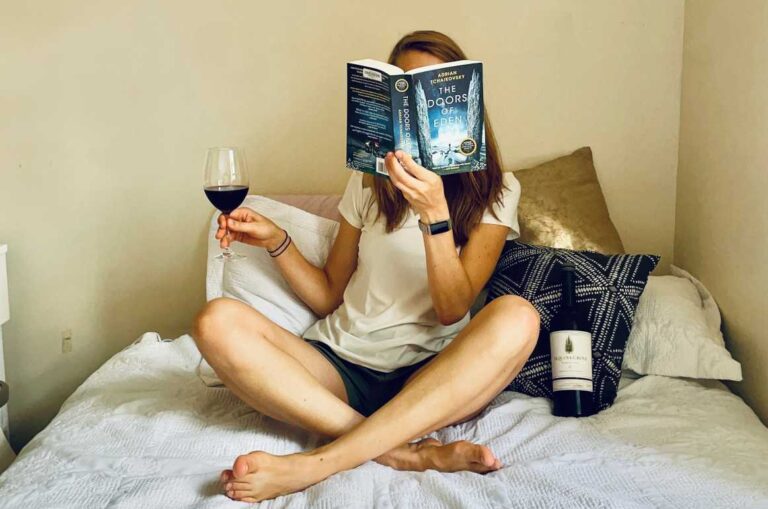 Reading book on bed with wine