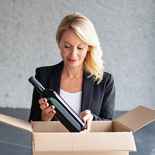 Woman pleased to be taking a wine bottle out of a box